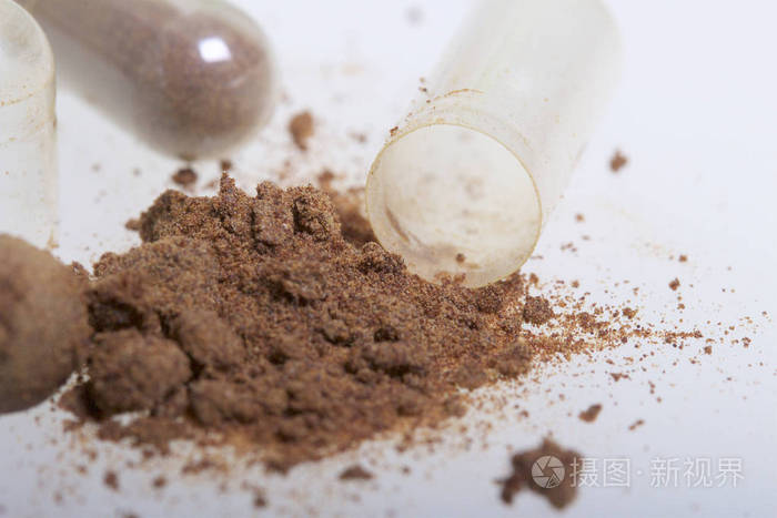 褐色药片散落在白色的表面.一个有效成分从一个药丸倾吐.从上面查看