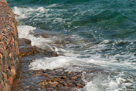 美丽清澈的绿松石海洋水面上的涟漪和明亮的飞溅在石海景背景, 水平图片