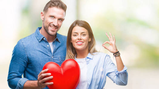年轻夫妇在爱持有红色心脏在孤立的背景做 ok 符号与手指, 优秀的符号