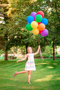 愉快的小女孩玩与大堆氦填充五颜六色的气球在公园