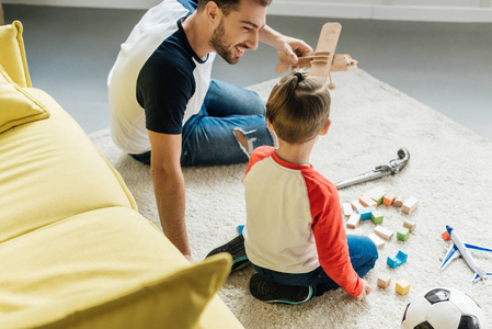 父亲和可爱的小儿子玩木块在地板上在家里
