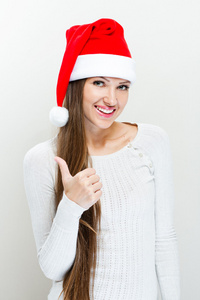 圣诞老人帽子和表演的女孩拇指向上
