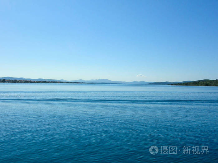 美丽的平静的海与岩石和山在蓝天和晴朗的天照片-正版商用图片06kppx