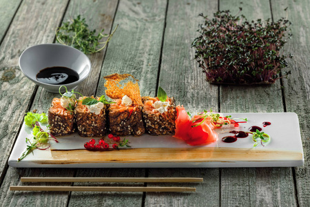传统健康的日本餐生鱼片由鲑鱼鱼制成的方形盘子。鱼卷在木桌上