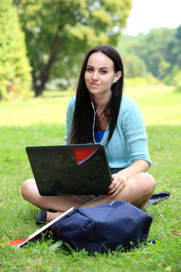 坐在草丛中笔记本电脑在校园工作的在校大学生