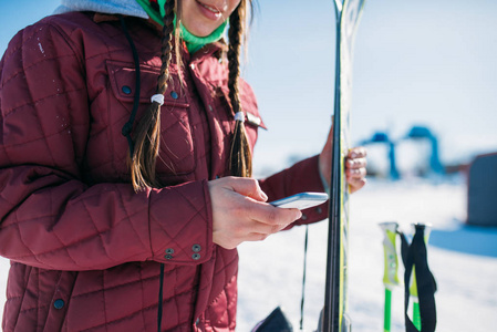 女滑雪者手持滑雪板和手提电话。冬季活跃的运动, 极端的生活方式。下坡或高山滑雪