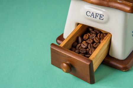 咖啡豆在手捧的咖啡研磨机上的嫩绿色 bac