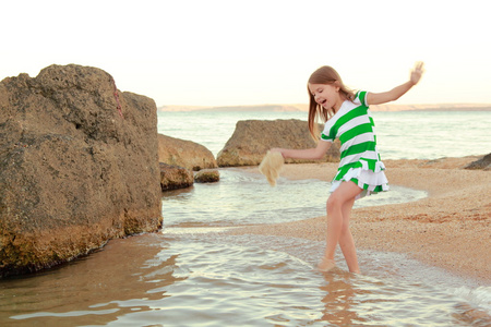 在日落时在沙滩上散步的情感快乐年轻女孩