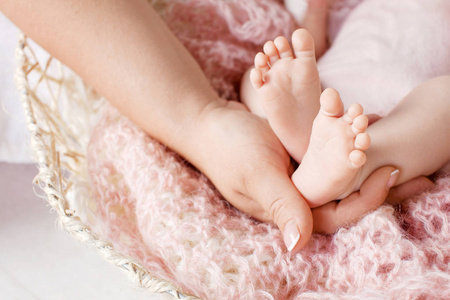 婴儿脚在母亲的手。小婴儿的脚在女性手特写。妈妈和她的孩子。幸福的家庭观念。美丽的亲子概念形象