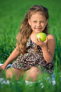 在与苹果公司的绿色草地上的快乐女孩