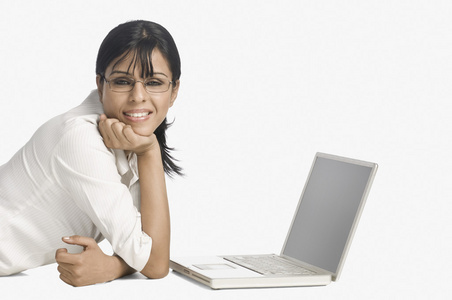 女人躺在一台笔记本电脑和微笑