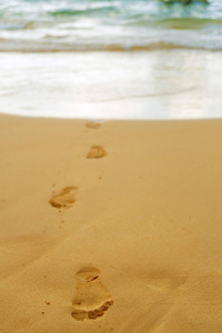 一个人赤脚在沙滩上的足迹, 从海洋到日