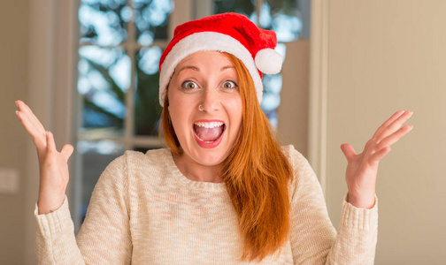 戴着圣诞老人帽子的红发女郎非常高兴和兴奋, 获胜者表情用灿烂的微笑尖叫着庆祝胜利, 举起双手