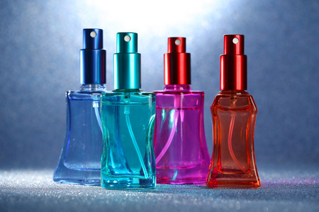 妇女在明亮的背景上的美丽瓶中的香水