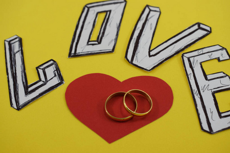 字爱在黄色背景与心脏和订婚戒指