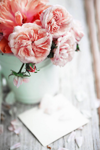 在木桌上的空白卡片的花瓶的牡丹玫瑰