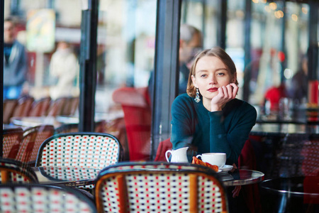 法国巴黎传统咖啡馆里喝咖啡和使用手机的年轻优雅女人