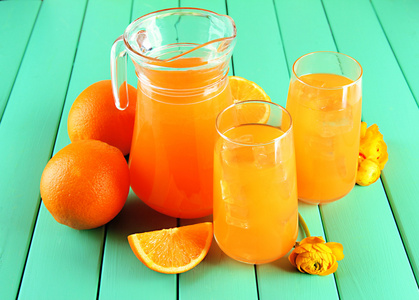 眼镜和投手的橙汁在蓝色木制背景