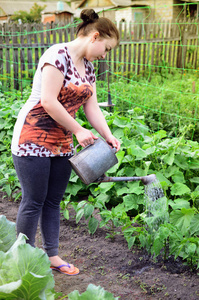 女孩浇灌从浇灌的罐头庭院