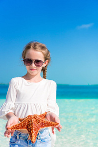 可爱的小女孩，用空的白色沙滩上的海星