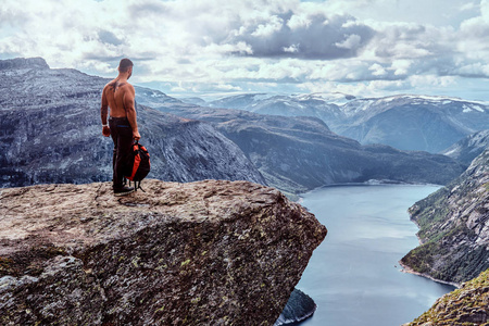 旅游男子站在 Trolltunga 和欣赏挪威峡湾的美丽景色