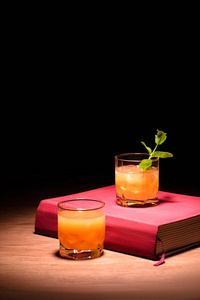 橙色酒精鸡尾酒与薄荷在桌上粉红色书