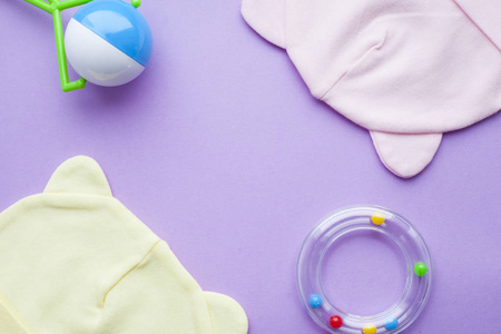婴儿黄色的赃物。儿童鞋和玩具的紫色背景。新生儿。顶部视图