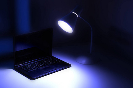 台灯照在桌子上, 一台笔记本电脑, 一间暗室, 一个书房, 键盘只是被, 软对焦