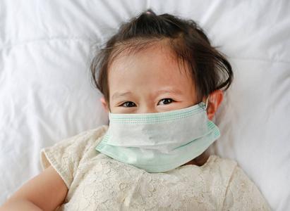 亚洲小女孩戴着防护面具躺在床上