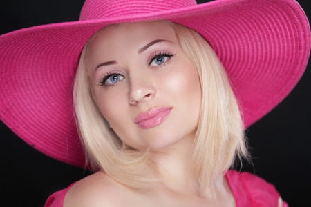 美容时尚女孩画像。金发碧眼的女性，在孤立的粉红色帽子