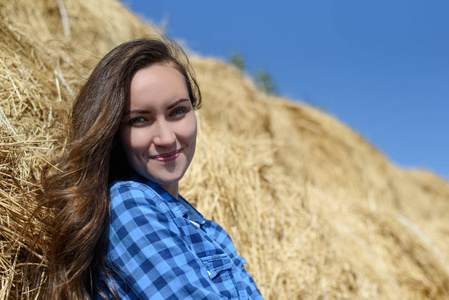 微笑的年轻褐发女郎站在干草堆在蓝色男人的格子衬衫, 复制空间