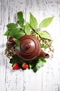 茶壶配干的花卉和草药成分，颜色木制背景上的天然茶