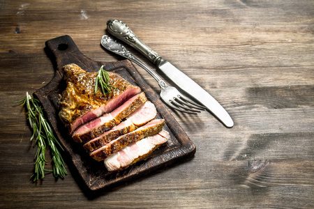 在切板上配有香料的牛肉烤架。在木桌上