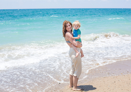 快乐妈妈和小宝贝儿子在海滩度假很开心