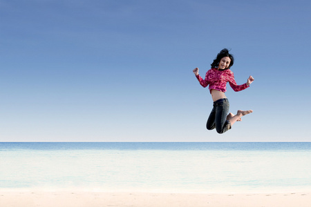 美丽的女孩在海滩上跳跃