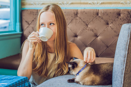 喝咖啡和抚摸猫的年轻妇女