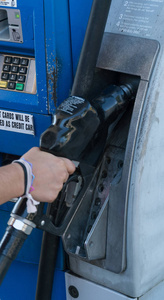 女性手举燃油喷嘴在加油站泵上填充汽车油箱高辛烷值的动力驱动汽车