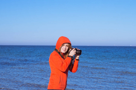 年轻女子与单反相机, 夏季海和 blus 的天空背景