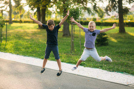 两个孩子在公园里玩耍。两个穿着 t恤衫和短裤的漂亮男孩笑得很开心。他们吃冰淇淋, 跳, 跑。夏天是晴天