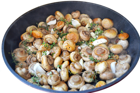 与百里香和大蒜素白色衬底上分离出一个平底锅烤的蘑菇香菇