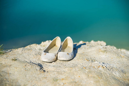 在沙滩上关闭女性白皮鞋。暑假概念