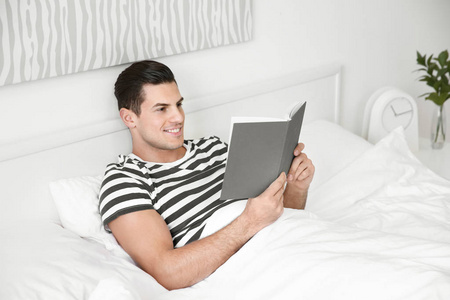 年轻英俊的人在家读书在床上