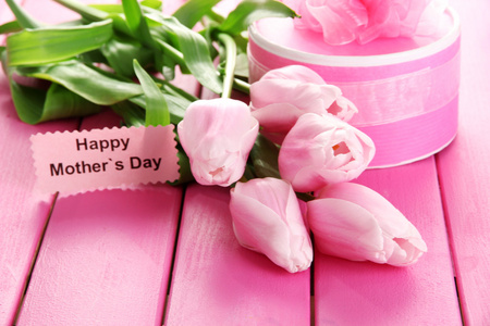 束美丽的郁金香和粉红色的木制背景上母亲节的礼物