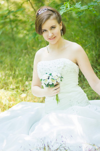 自然美丽的年轻新娘的画像。年轻女子在他们手中捧着一小束白玫瑰