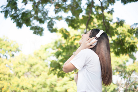 一个微笑的女孩的肖像听音乐, 而放松自然公园户外