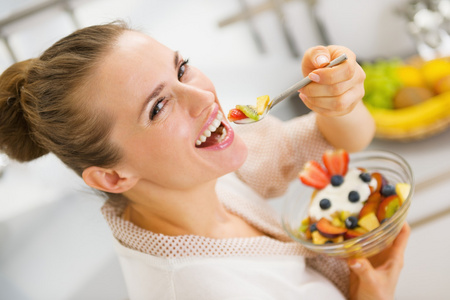 快乐年轻的主妇吃水果沙拉图片