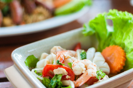 虾和鱿鱼辣沙拉在菜木背景, 泰国传统混合海鲜