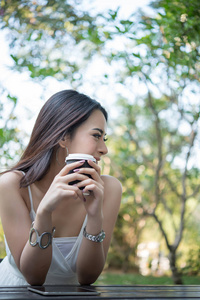 手持咖啡杯的年轻女子坐在户外享受大自然