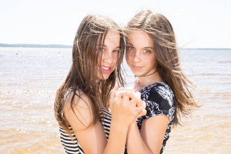 美丽的两个双胞胎姐妹一起在海滩上享受特写美女肖像