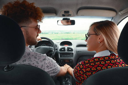 年轻的情侣坐着车到他们的幸福中, 握住他们的手, 微笑着看着对方。自由, 爱和团结的概念